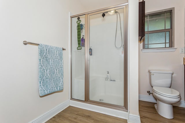 full bathroom featuring toilet, a shower stall, baseboards, and wood finished floors