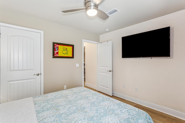 bedroom with ceiling fan, wood finished floors, visible vents, and baseboards