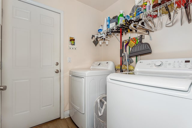 laundry area with laundry area, washing machine and dryer, and wood finished floors