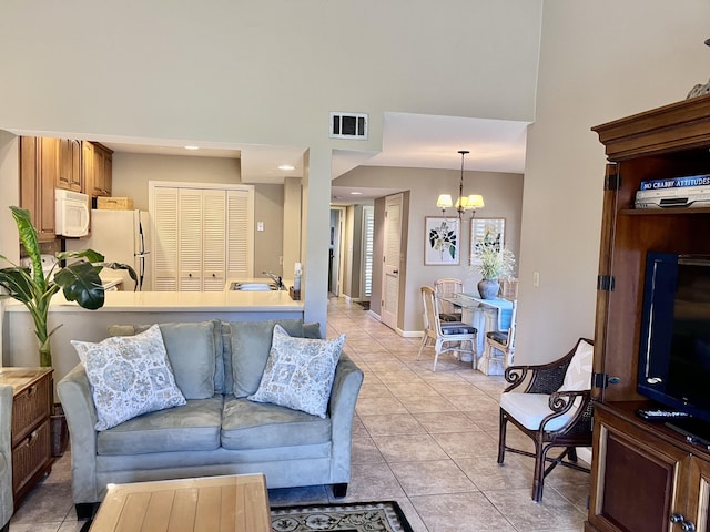 tiled living room featuring a towering ceiling, sink, and a chandelier