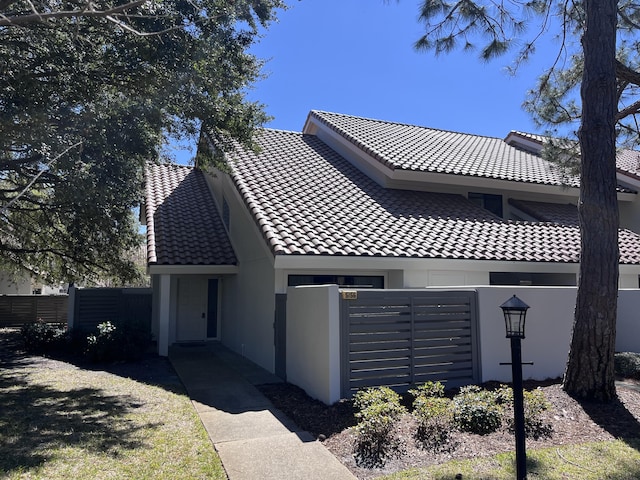 view of front of property featuring a tiled roof, a fenced front yard, and stucco siding