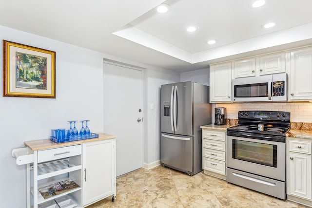 kitchen featuring white cabinetry, backsplash, appliances with stainless steel finishes, and light stone counters
