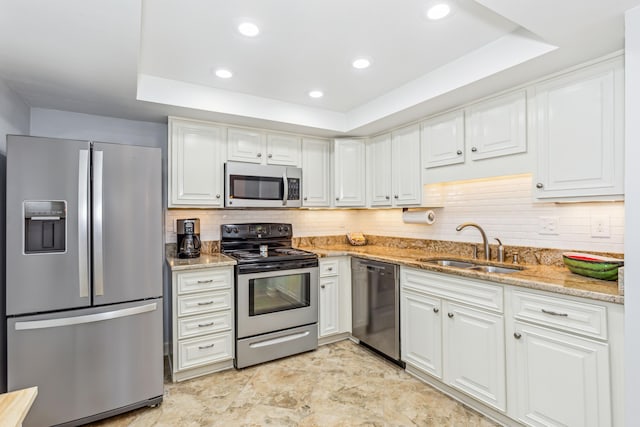 kitchen featuring a raised ceiling, appliances with stainless steel finishes, sink, and white cabinets