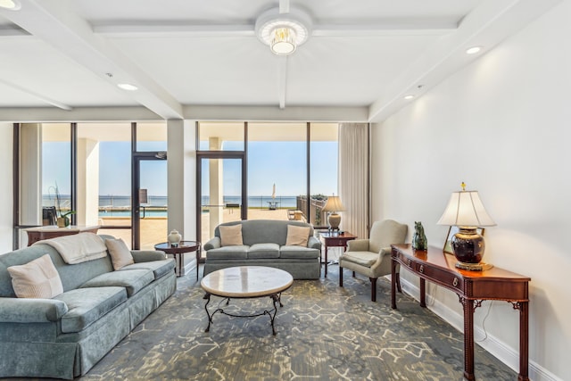 living room with beam ceiling, a water view, plenty of natural light, and a wall of windows