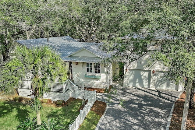 view of front of property with a garage, aphalt driveway, stairs, and metal roof