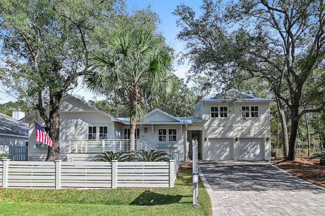 view of front of home featuring a fenced front yard, decorative driveway, and an attached garage