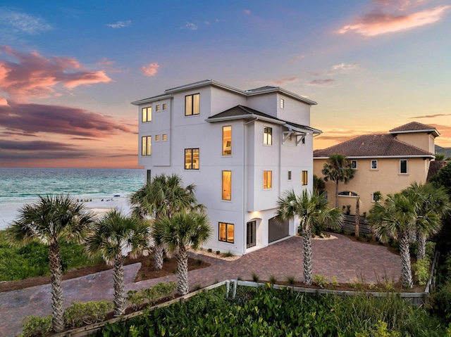 back house at dusk with a water view and a garage