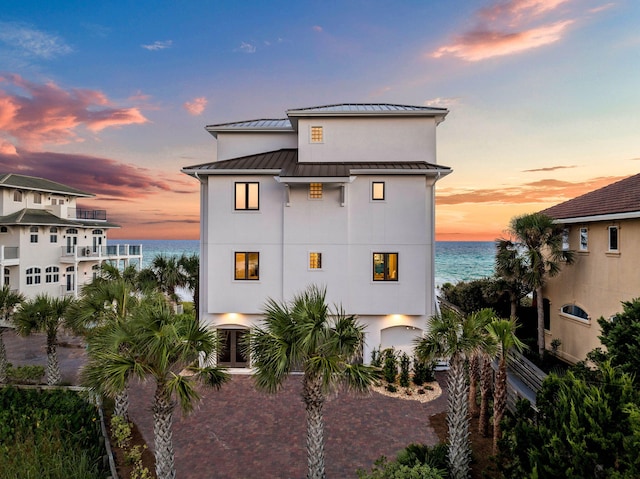 back house at dusk featuring a water view and a garage