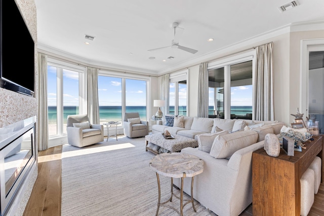 living room with a water view, plenty of natural light, crown molding, and wood-type flooring