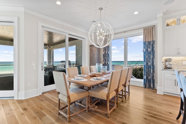 dining room with a water view, ornamental molding, a chandelier, and light hardwood / wood-style flooring