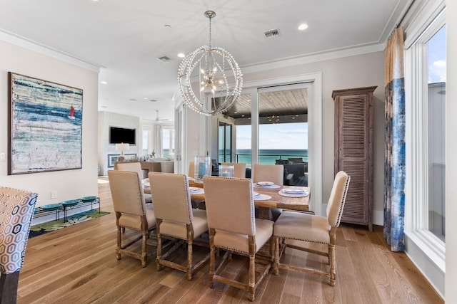 dining area featuring ornamental molding, light wood-type flooring, and a chandelier