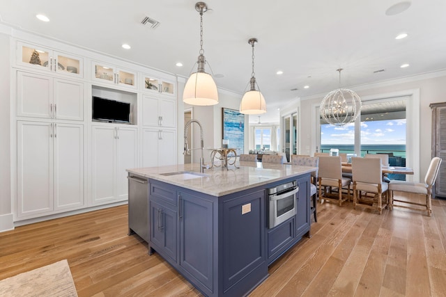 kitchen with sink, white cabinetry, pendant lighting, light stone countertops, and a kitchen island with sink