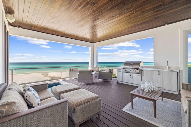 wooden deck with a view of the beach, an outdoor hangout area, and a water view