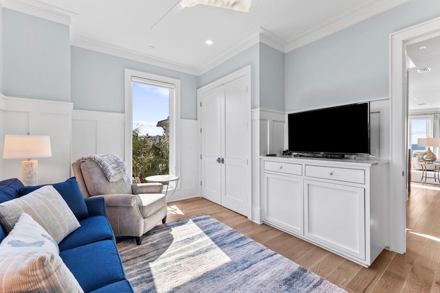 living room featuring crown molding, light hardwood / wood-style floors, and a healthy amount of sunlight