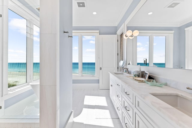 interior space with sink, light stone countertops, white cabinets, and a water view