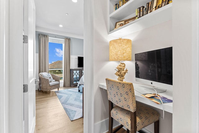 office area featuring crown molding, built in desk, and light hardwood / wood-style flooring