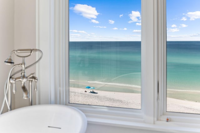 interior space with a tub, a water view, and a beach view