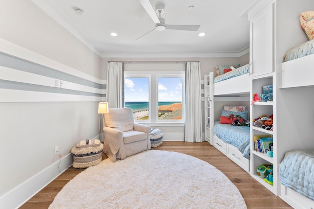 bedroom with crown molding, wood-type flooring, ceiling fan, and a water view