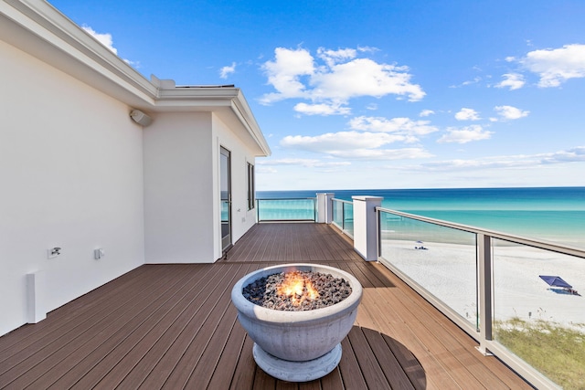 wooden deck featuring a view of the beach and a water view