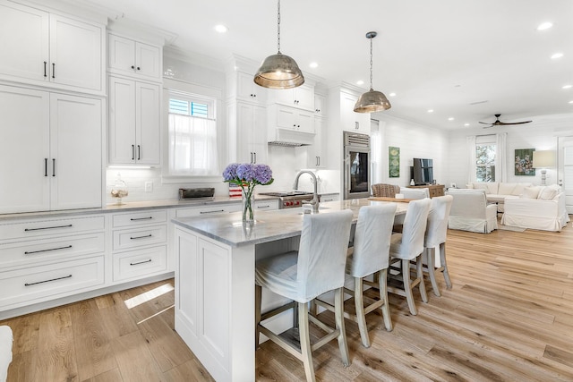 36 E Ruskin St, Santa Rosa Beach, FL 32459 - kitchen with white cabinetry, hanging light fixtures, a kitchen breakfast bar, an island with sink, and light hardwood / wood-style floors