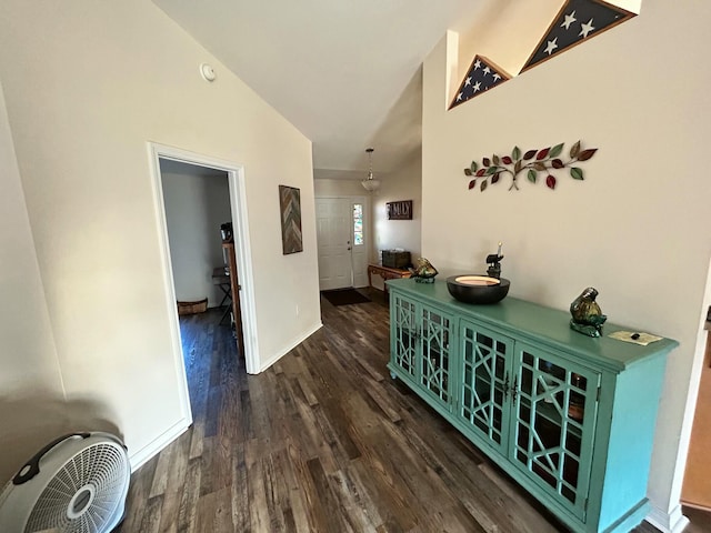 hallway featuring vaulted ceiling, baseboards, and wood finished floors