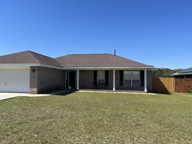 ranch-style home with fence, a shingled roof, a front lawn, a garage, and brick siding