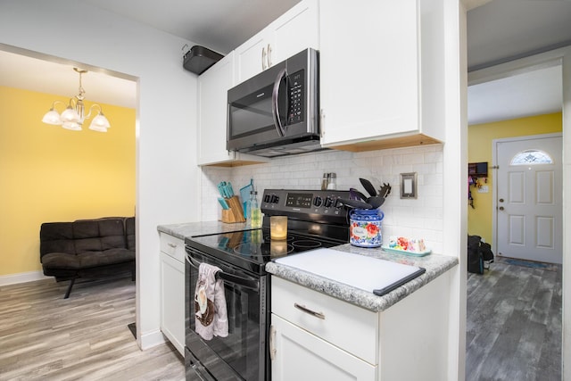 kitchen featuring tasteful backsplash, white cabinetry, light wood-type flooring, and black / electric stove