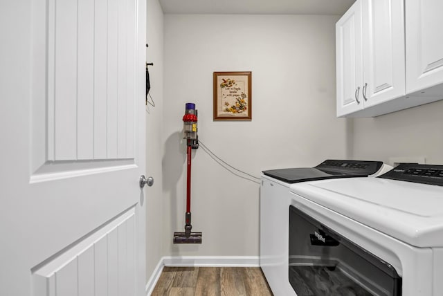 laundry area featuring baseboards, cabinet space, washing machine and clothes dryer, and wood finished floors