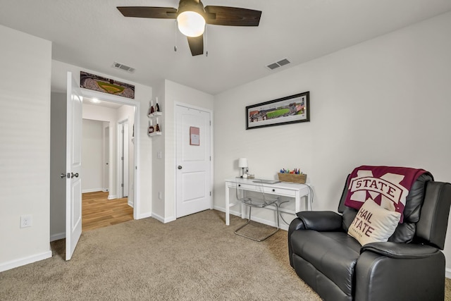 living area with carpet floors, visible vents, baseboards, and a ceiling fan