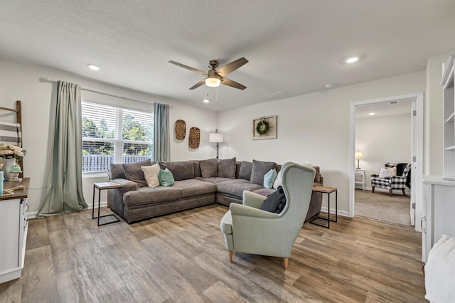 living area featuring light wood finished floors, ceiling fan, a textured ceiling, and recessed lighting