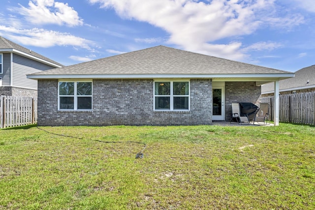 back of property featuring a fenced backyard, a yard, and brick siding