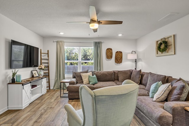 living area with a textured ceiling, baseboards, a ceiling fan, and light wood-style floors