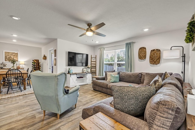 living area with light wood-style flooring, a textured ceiling, and recessed lighting