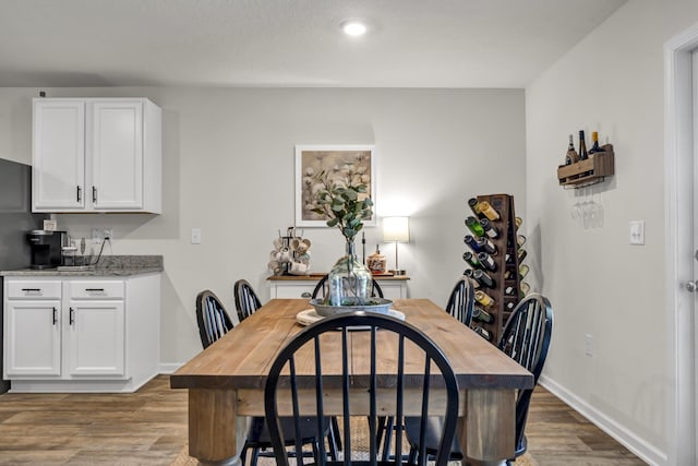 dining space with baseboards and wood finished floors