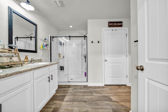 bathroom with a stall shower, visible vents, wood finished floors, vanity, and recessed lighting