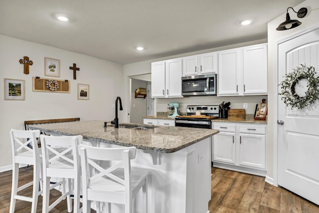 kitchen with white cabinetry, appliances with stainless steel finishes, dark wood-style flooring, and a sink