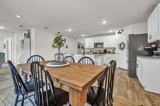 dining area featuring a textured ceiling, visible vents, wood finished floors, and recessed lighting