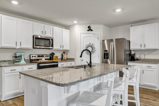 kitchen featuring light wood-style flooring, appliances with stainless steel finishes, white cabinets, and a sink