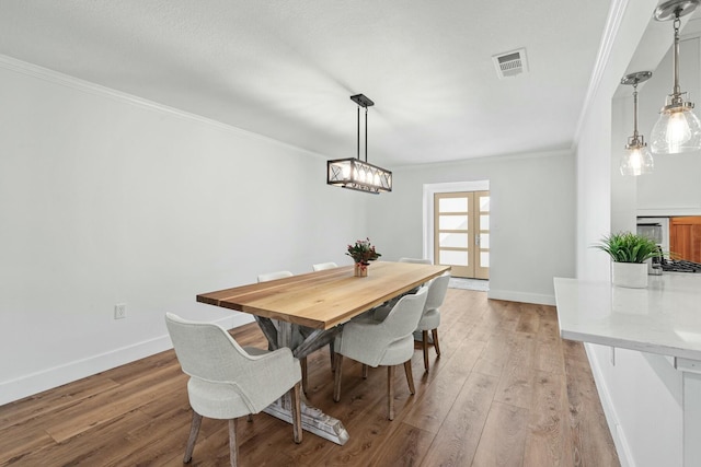 dining space with ornamental molding, visible vents, light wood-style flooring, and baseboards