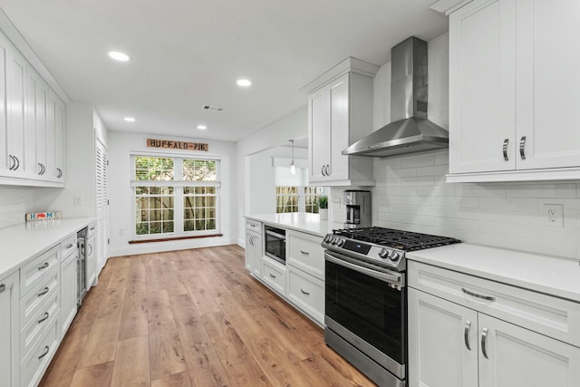 kitchen with wall chimney exhaust hood, light countertops, and stainless steel appliances