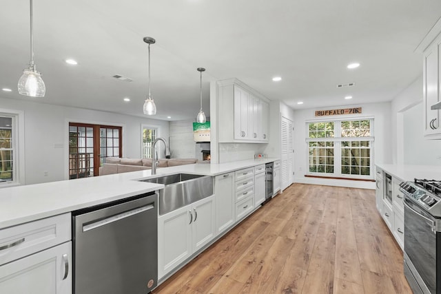 kitchen featuring light wood-style floors, appliances with stainless steel finishes, light countertops, and a sink