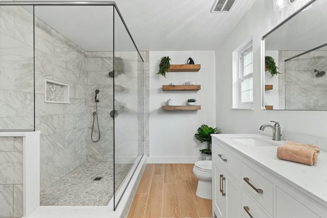 full bathroom featuring visible vents, toilet, wood tiled floor, vanity, and a walk in shower