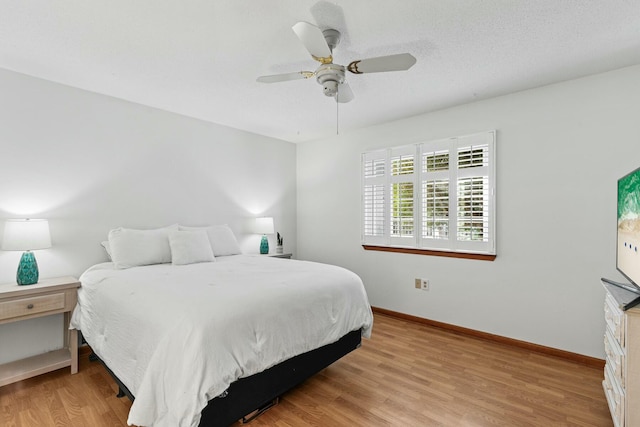 bedroom featuring light wood-type flooring, a ceiling fan, baseboards, and a textured ceiling