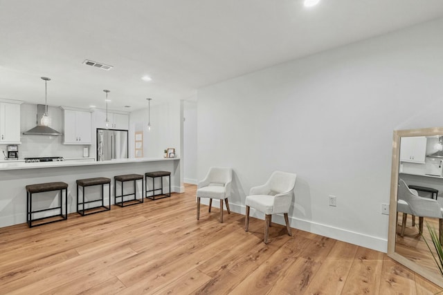 living area with light wood-style floors, recessed lighting, visible vents, and baseboards