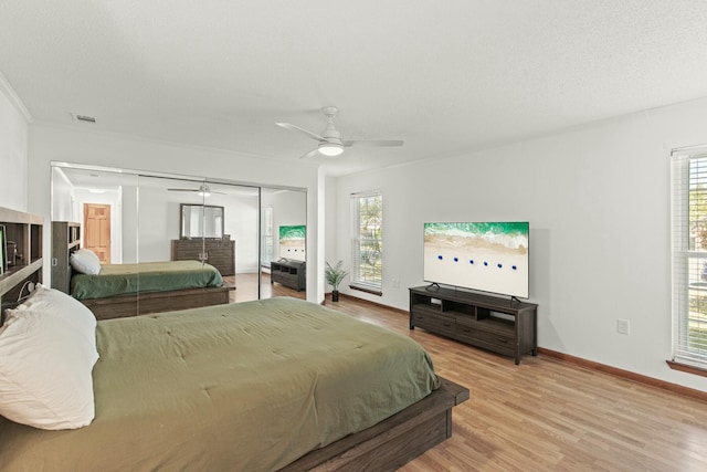 bedroom with light wood-style flooring, multiple windows, visible vents, and baseboards