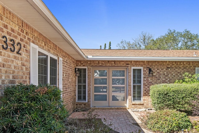 property entrance with brick siding and roof with shingles