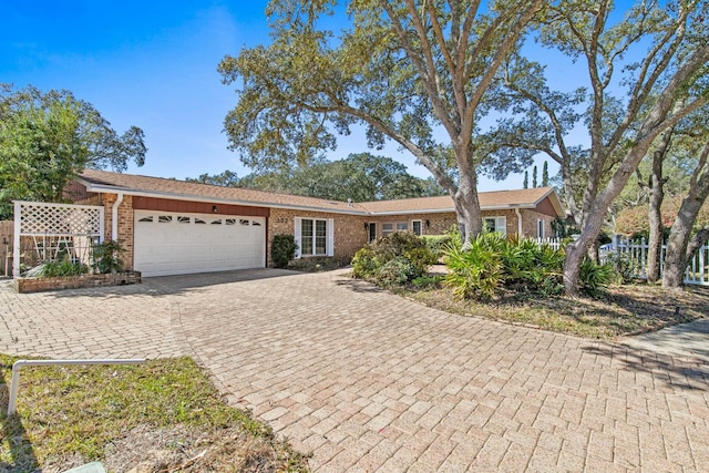 single story home featuring an attached garage, decorative driveway, and brick siding