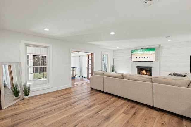 living area featuring visible vents, a fireplace, light wood-style flooring, and plenty of natural light