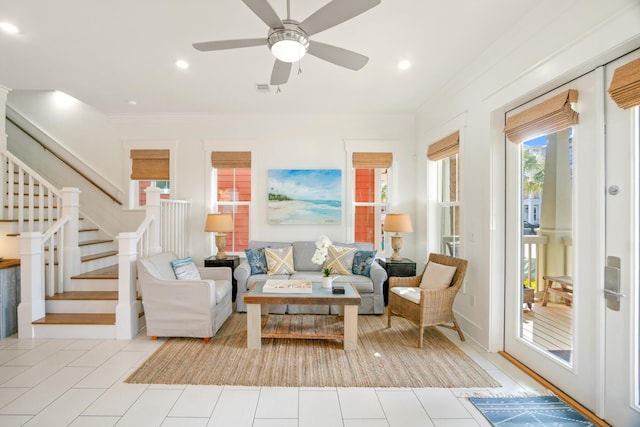 living room with stairs, ornamental molding, a ceiling fan, and tile patterned floors