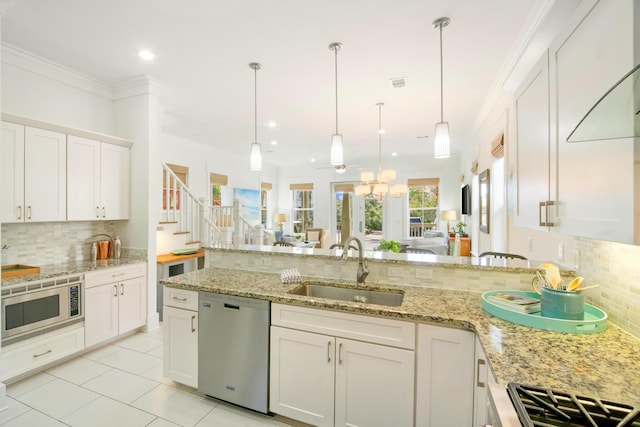 kitchen featuring tasteful backsplash, appliances with stainless steel finishes, ornamental molding, white cabinetry, and a sink